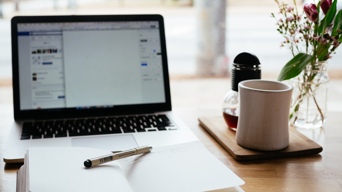 Portable et carnet ouvert sur un bureau de travail éditorial