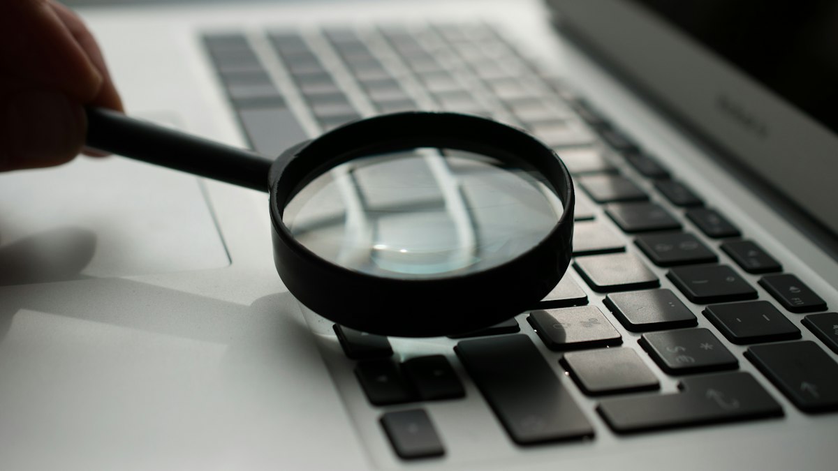 Loupe posée à côté d'un ordinateur portable, symbole d'un audit SEO technique