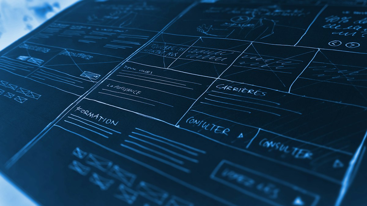 Maquettes de pages web dessinées à la main sur fond bleu, représentant l'architecture d'un site